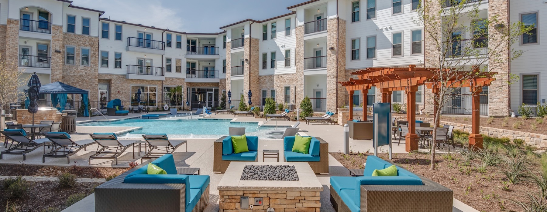 a courtyard with a fire pit, chairs and a pool