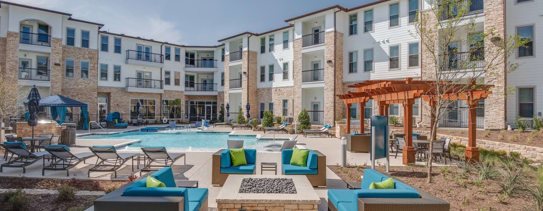 a courtyard with a fire pit, chairs and a pool